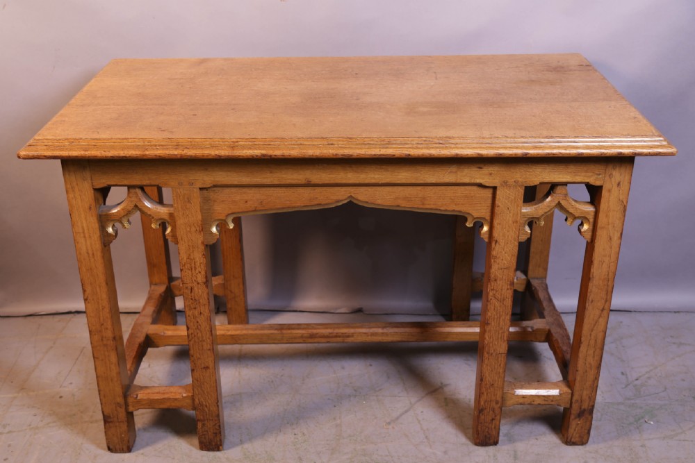 A 19th-century oak Gothic Revival serving table featuring carved pointed arch spandrels and a low box stretcher.