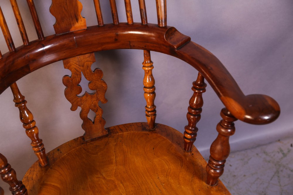 A warm brown yew wood Windsor chair with a hoop back, central pierced splat, wide armrests, turned legs, and H-stretcher supports. View VIII