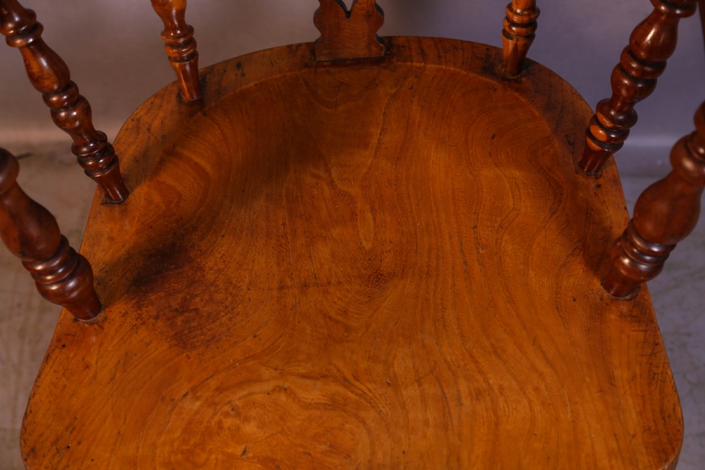 A warm brown yew wood Windsor chair with a hoop back, central pierced splat, wide armrests, turned legs, and H-stretcher supports. View IX