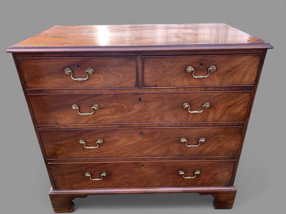 A Georgian mahogany chest of drawers featuring a two short over three long drawer arrangement with brass swan-neck handles and bracket feet.