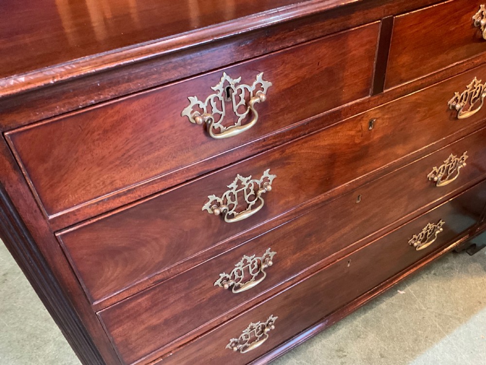 A Georgian mahogany chest of drawers featuring a two-over-three drawer arrangement, ornate brass swan-neck handles, and bracket feet. View IV