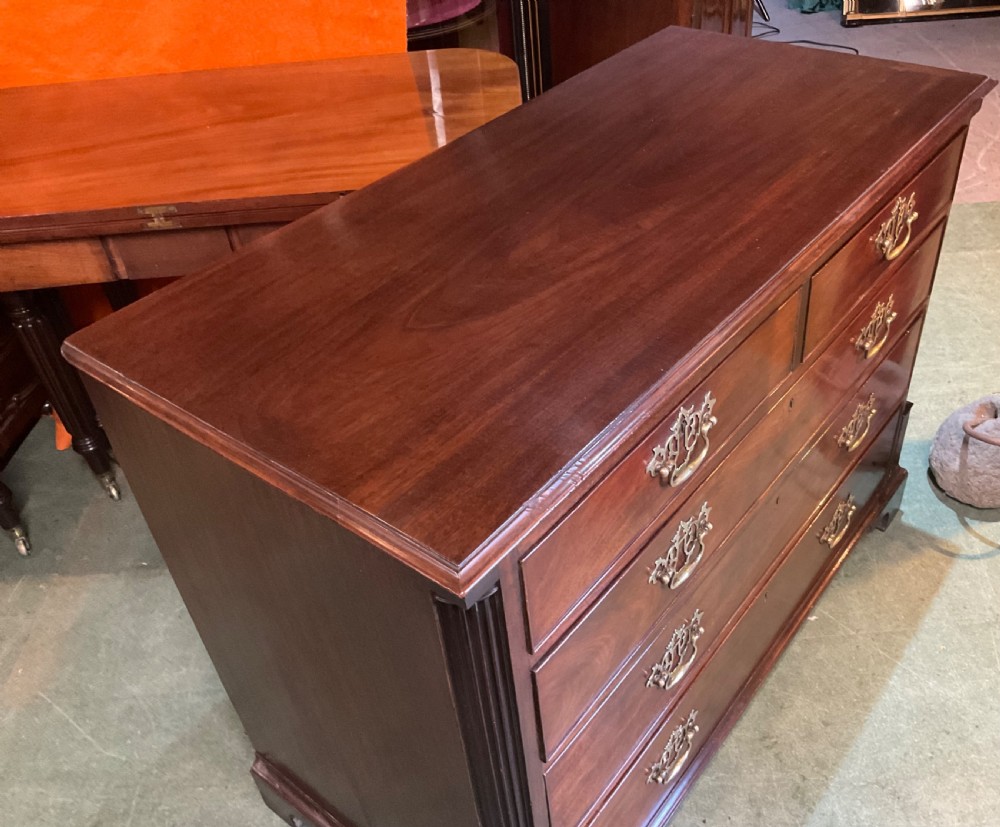 A Georgian mahogany chest of drawers featuring a two-over-three drawer arrangement, ornate brass swan-neck handles, and bracket feet. View V