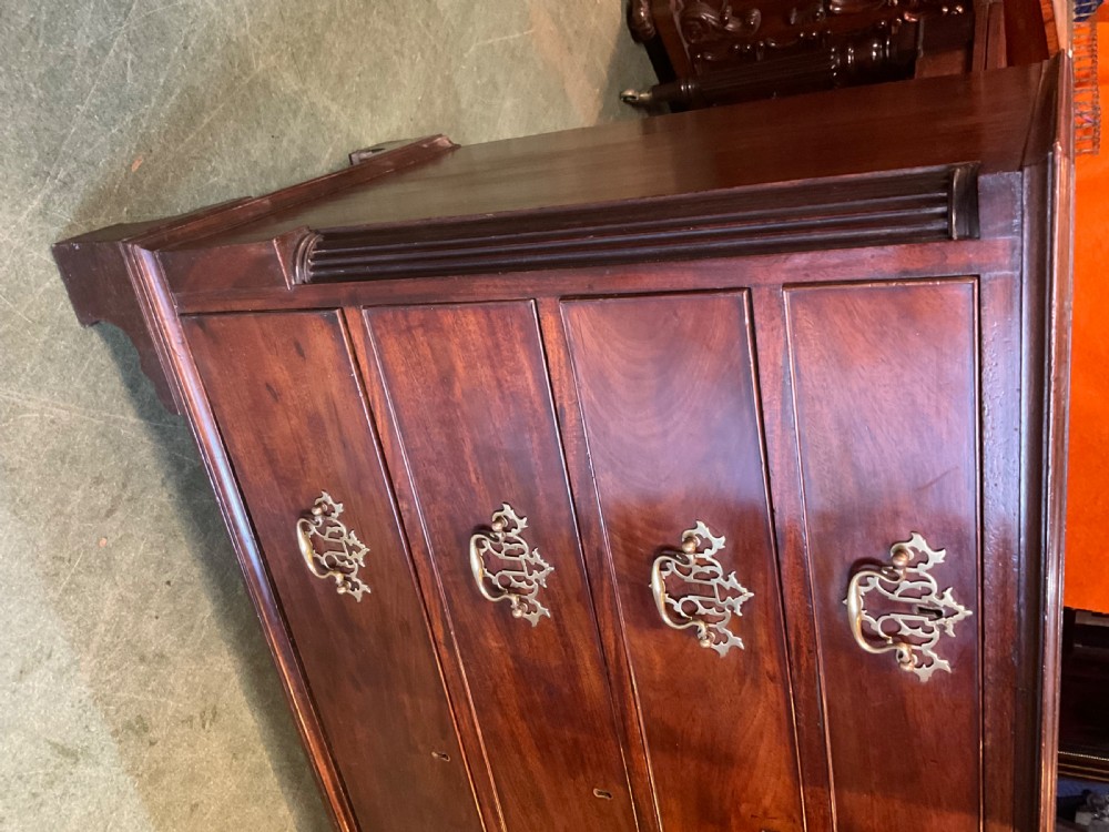 A Georgian mahogany chest of drawers featuring a two-over-three drawer arrangement, ornate brass swan-neck handles, and bracket feet. View VI