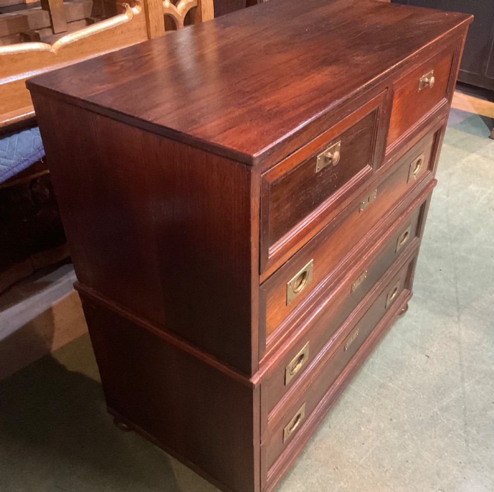 An antique padouk wood campaign chest of drawers featuring two short over three long drawers with recessed brass handles and turned feet. View V