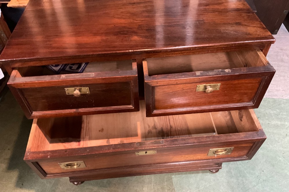 An antique padouk wood campaign chest of drawers featuring two short over three long drawers with recessed brass handles and turned feet. View VI