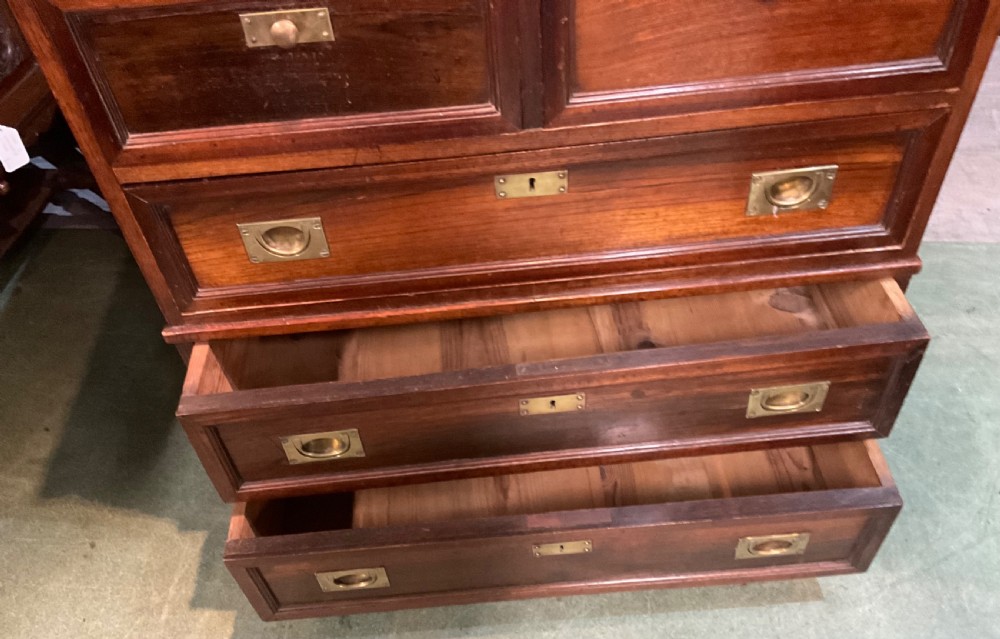 An antique padouk wood campaign chest of drawers featuring two short over three long drawers with recessed brass handles and turned feet. View VII