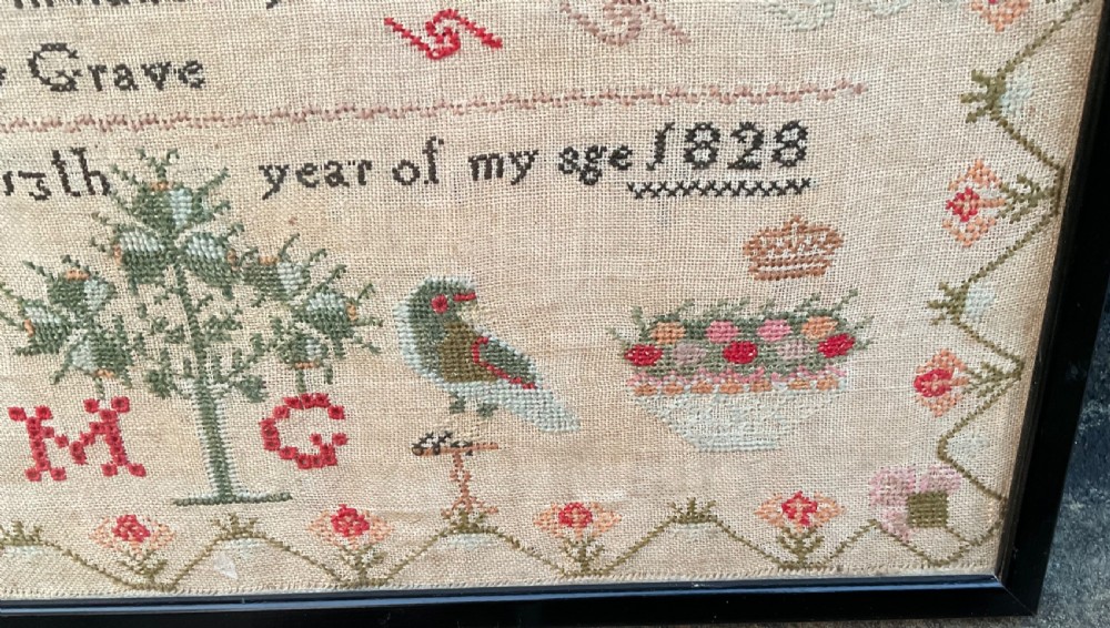 A framed antique Georgian needlework sampler featuring alphabets, numbers, a stitched verse, and various motifs including a central tree, animals, and floral borders on a neutral linen background. View III