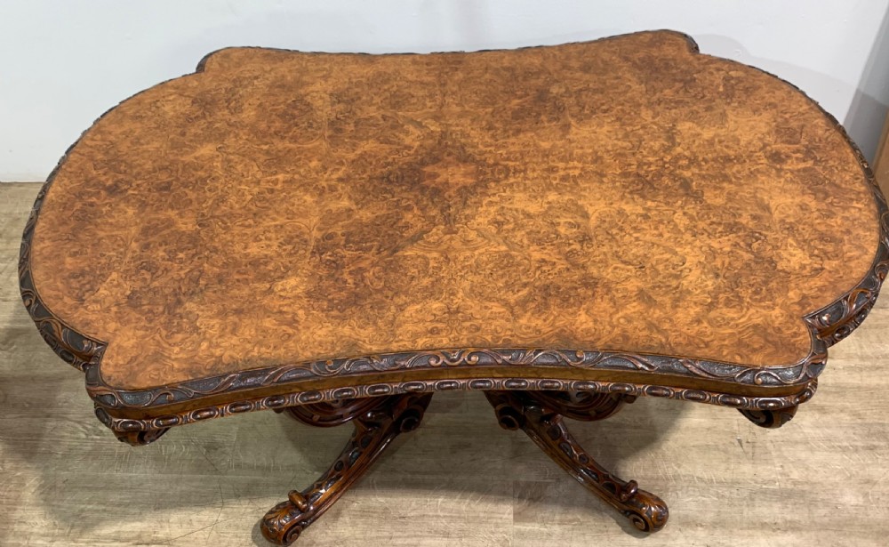 A rectangular Victorian burr walnut centre table with a figured top, carved edges, and a multi-scroll pedestal base. View VIII