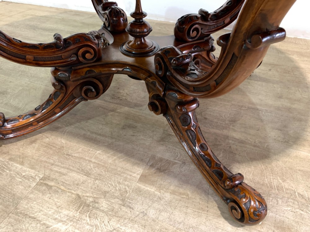 A rectangular Victorian burr walnut centre table with a figured top, carved edges, and a multi-scroll pedestal base. View X
