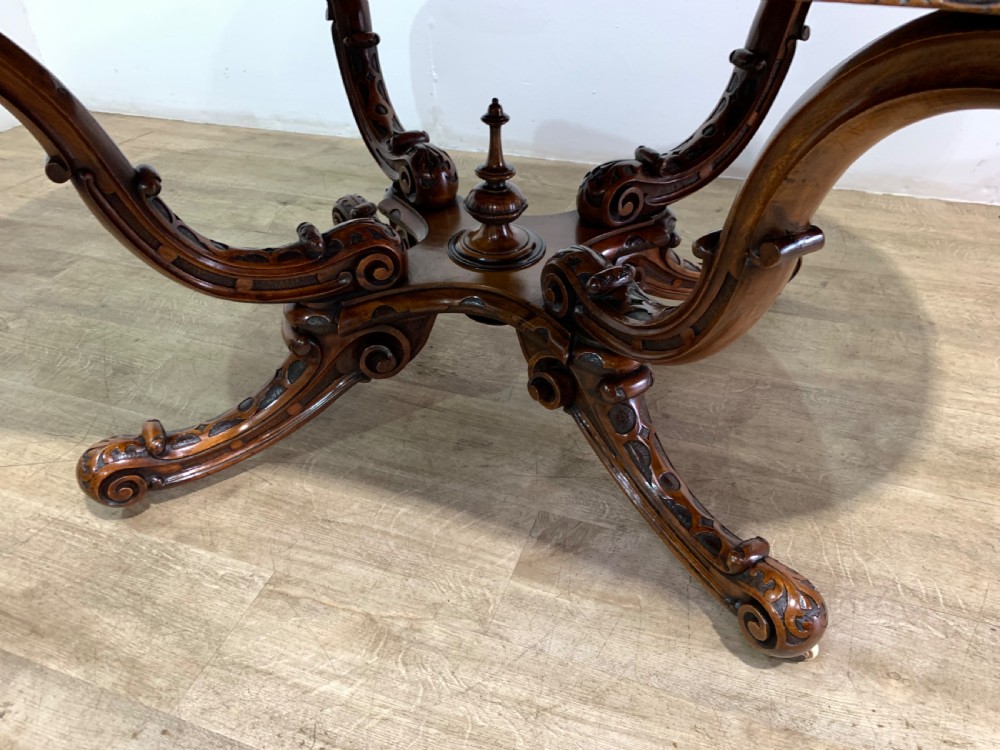 A rectangular Victorian burr walnut centre table with a figured top, carved edges, and a multi-scroll pedestal base. View XII