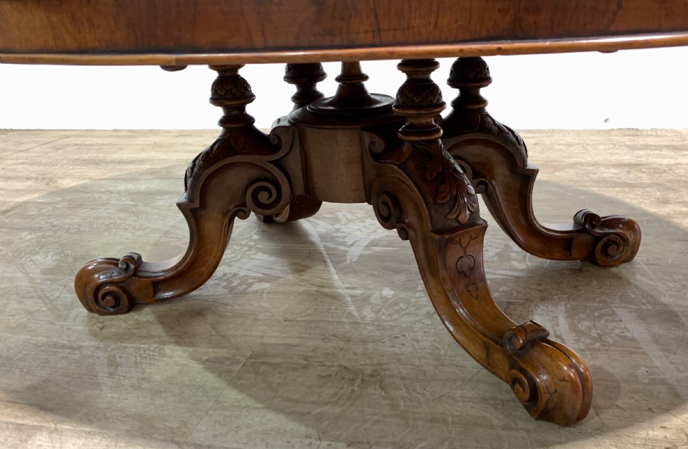An oval Victorian coffee table featuring a highly figured burr walnut top and scrolled carved legs. View V