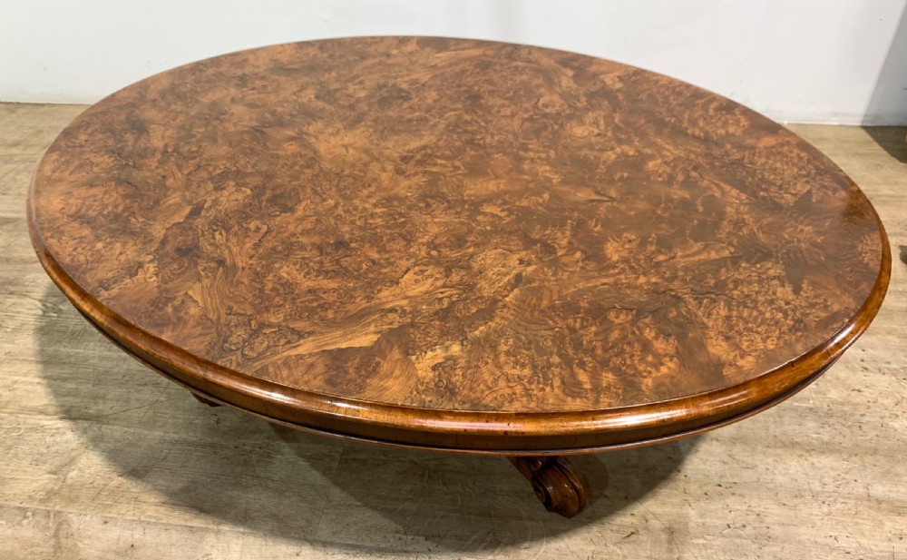 An oval Victorian coffee table featuring a highly figured burr walnut top and scrolled carved legs. View VI
