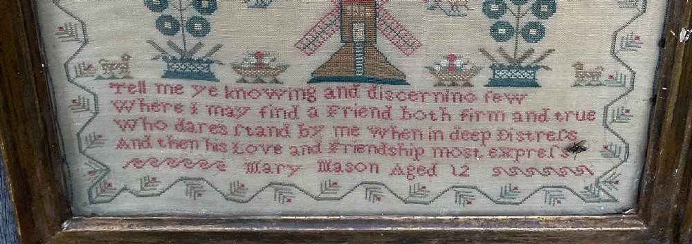 A framed antique needlework sampler on cream linen featuring embroidered trees, stags, flowers, a central windmill, a poetic verse, and the makers signature Mary Mason Aged 12. View VI