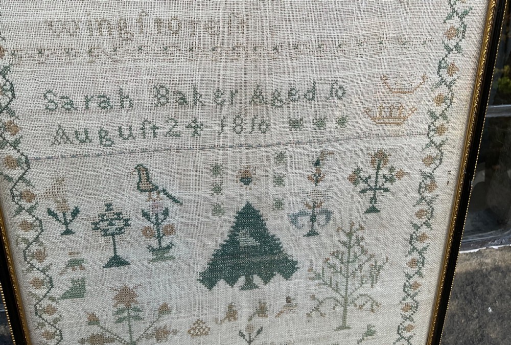 A framed 1810 Georgian linen sampler featuring hand-stitched religious verse, tree motifs, geometric borders, and text reading Sarah Baker Aged 10 August 24 1810. View IV