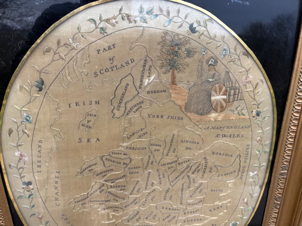 A circular Georgian silk needlework map of England and Wales with a floral border, presented in a square gilt frame. View II