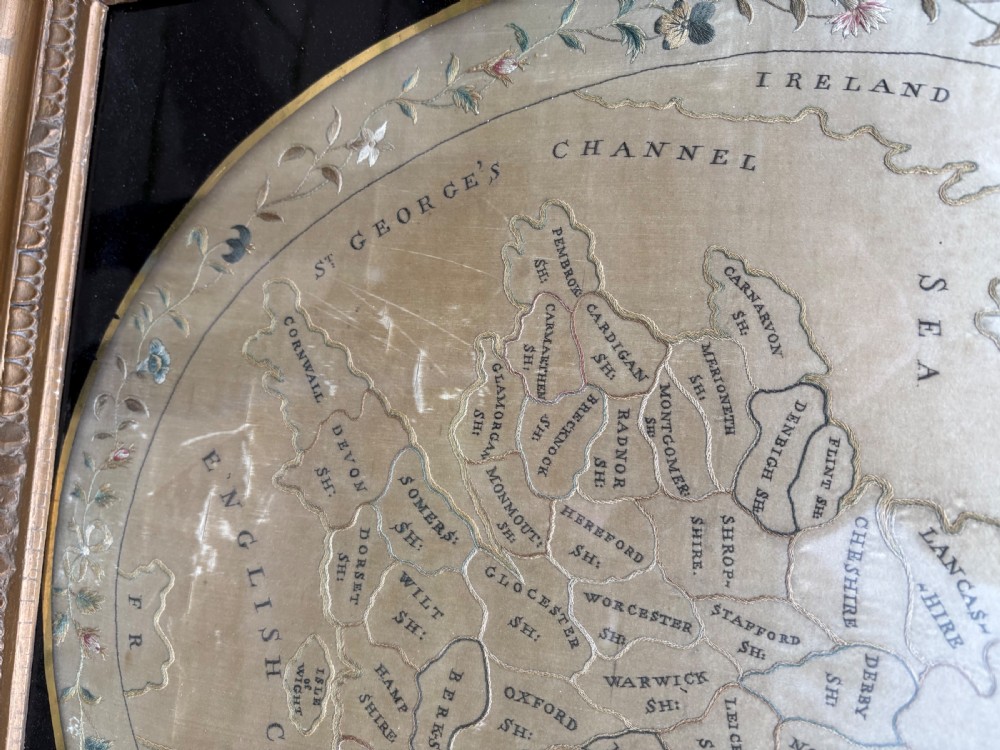 A circular Georgian silk needlework map of England and Wales with a floral border, presented in a square gilt frame. View III