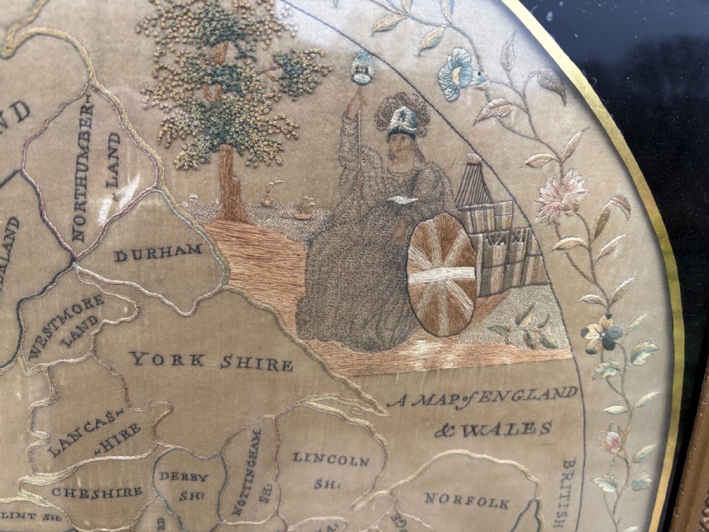 A circular Georgian silk needlework map of England and Wales with a floral border, presented in a square gilt frame. View IV