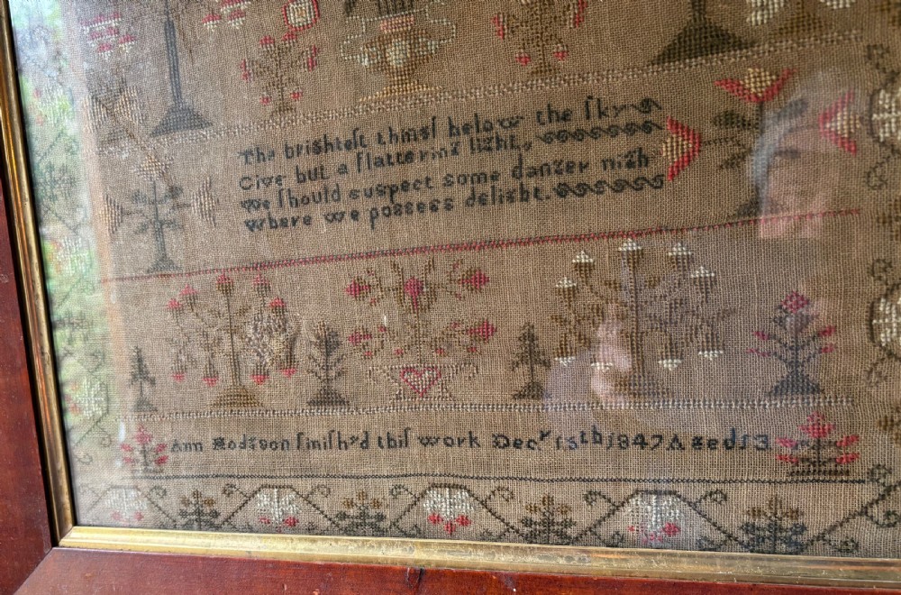 Framed Victorian needlework sampler featuring embroidered alphabets, floral motifs, a central verse, and a signature line dated 1847 set within a wide wooden frame. View IV