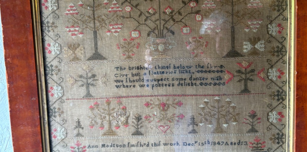 Framed Victorian needlework sampler featuring embroidered alphabets, floral motifs, a central verse, and a signature line dated 1847 set within a wide wooden frame. View VII