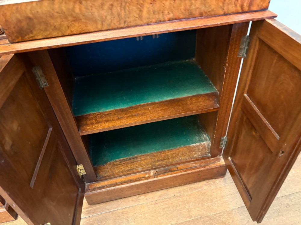 A Victorian walnut collectors cabinet featuring glazed upper doors revealing shallow specimen drawers, a spindled top gallery, a central mirrored recess, and a lower panelled cupboard base with brass handles. View VI