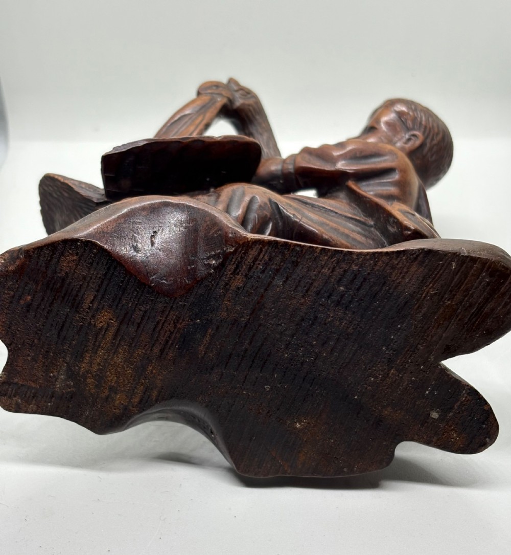A hand-carved dark wood sculpture depicting a boy sitting alongside a large bird with detailed wing carving. View VIII