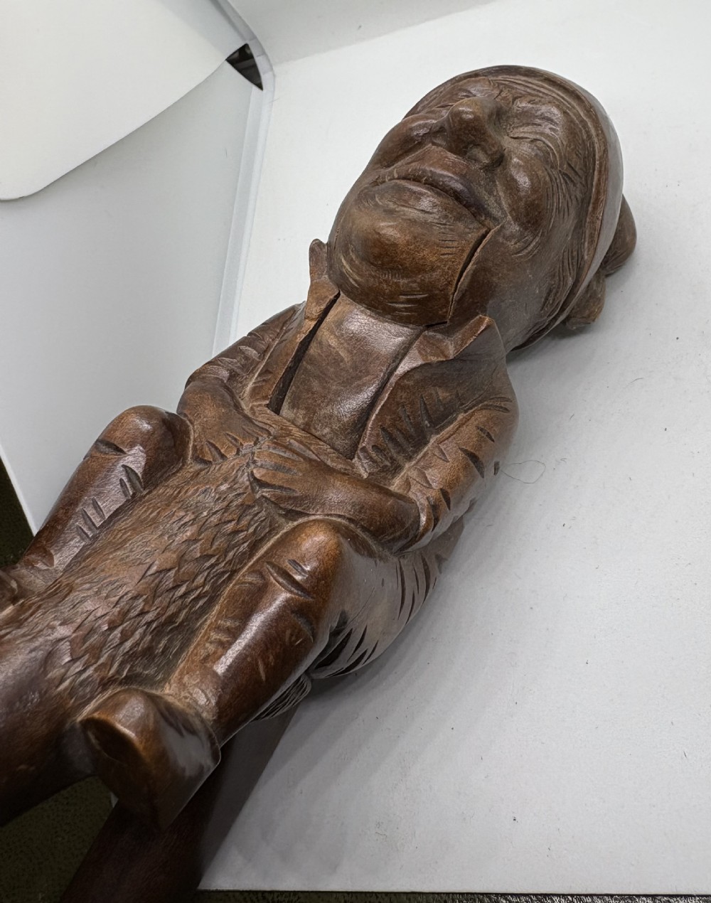 A hand-carved dark brown wood Black Forest nutcracker in the form of a seated figure with an integrated lever mechanism.