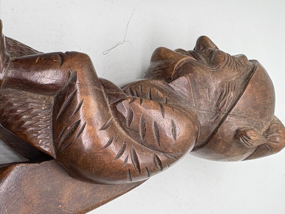 A hand-carved dark brown wood Black Forest nutcracker in the form of a seated figure with an integrated lever mechanism. View IV