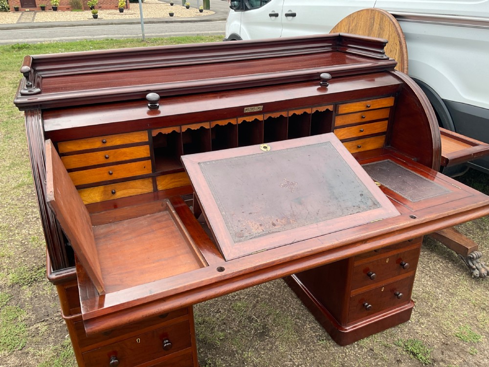 A 19th-century dark mahogany cylinder desk featuring a curved roll-top cover above twin drawer pedestals. View XVII