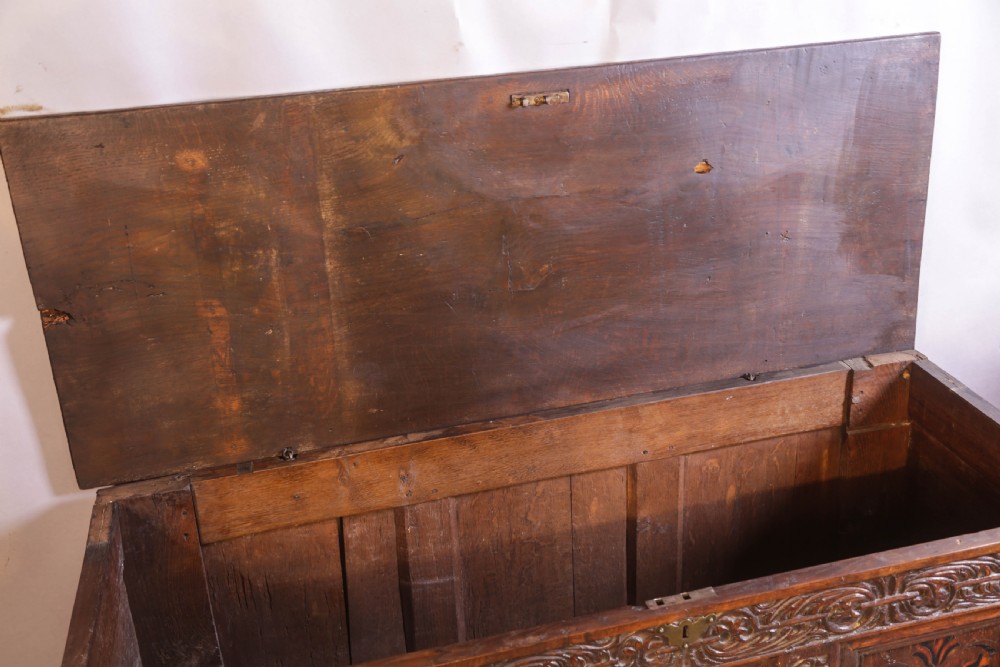 An antique carved oak coffer featuring three floral inlaid panels, carved frieze work, and two lower drawers with brass handles. View XIV