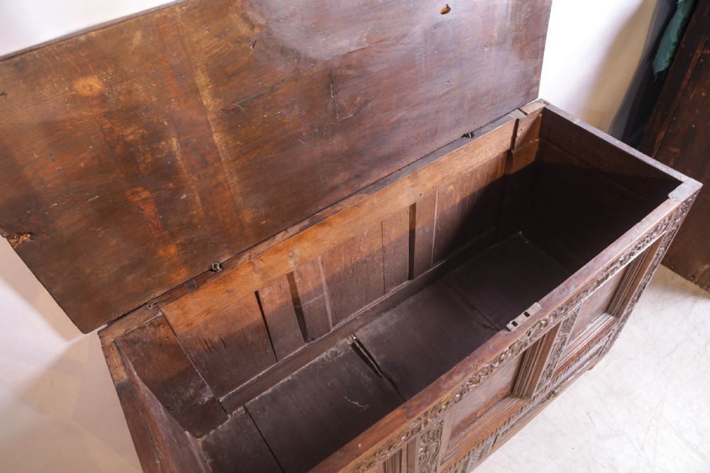An antique carved oak coffer featuring three floral inlaid panels, carved frieze work, and two lower drawers with brass handles. View XV