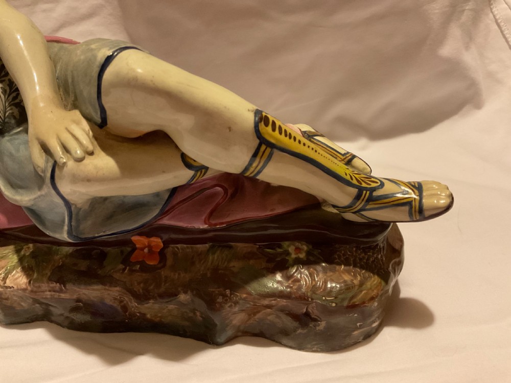 A pair of antique ceramic reclining figures depicting Mark Antony and Cleopatra on moulded bases. View V