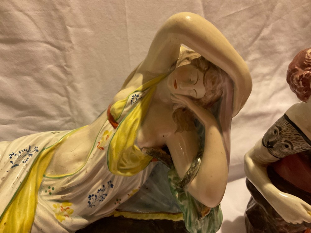 A pair of antique ceramic reclining figures depicting Mark Antony and Cleopatra on moulded bases. View VII