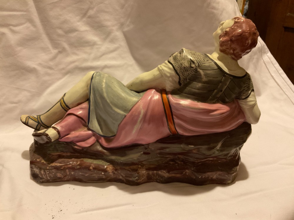 A pair of antique ceramic reclining figures depicting Mark Antony and Cleopatra on moulded bases. View IX