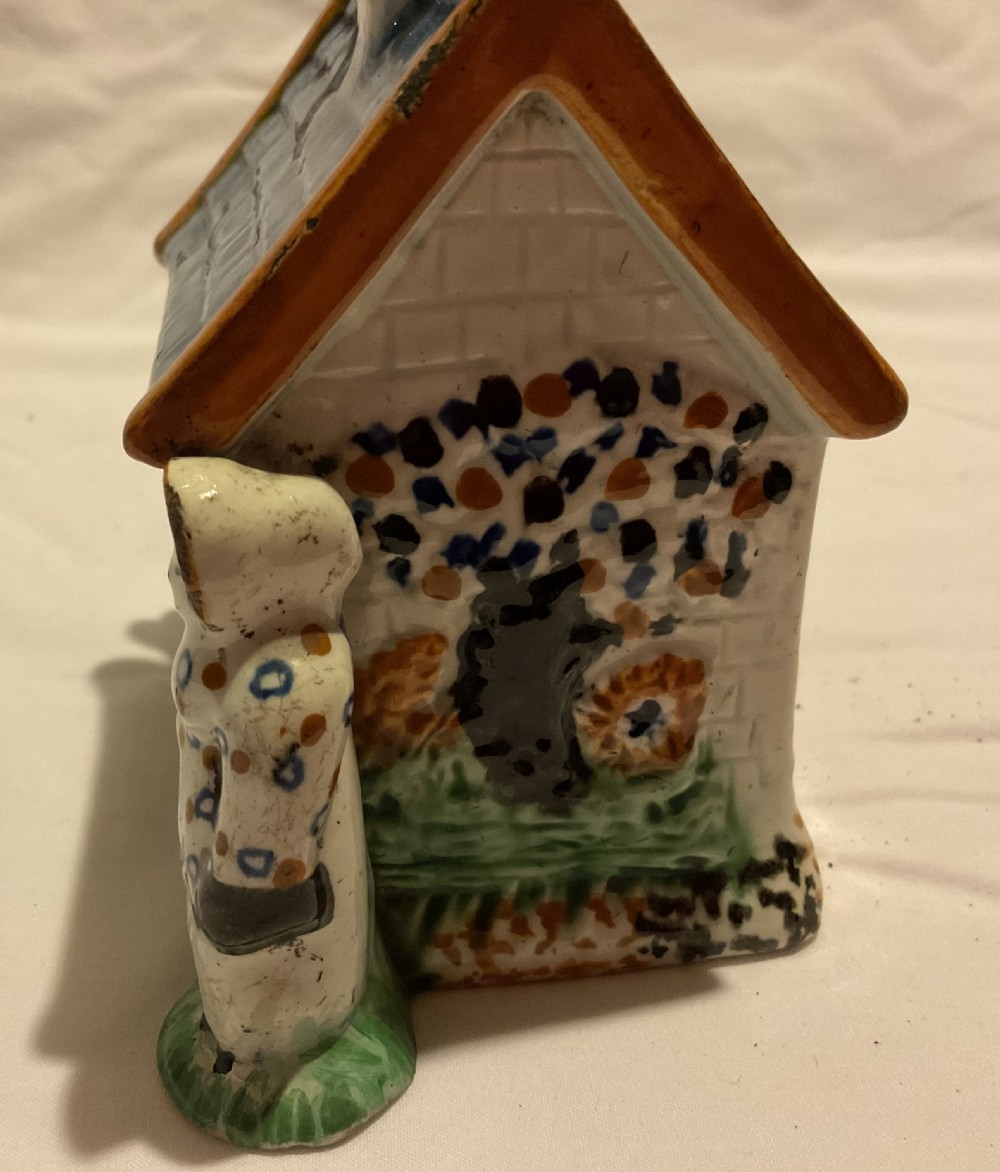 A Regency Prattware earthenware cottage figure featuring a blue tiled roof, central chimney, and relief figures standing on either side. View V
