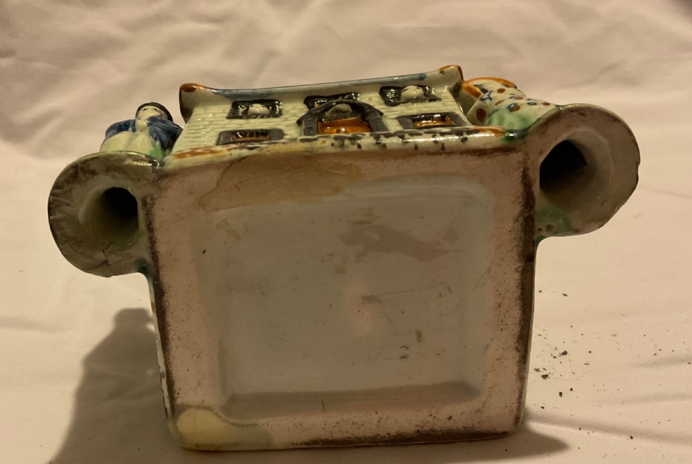 A Regency Prattware earthenware cottage figure featuring a blue tiled roof, central chimney, and relief figures standing on either side. View VII