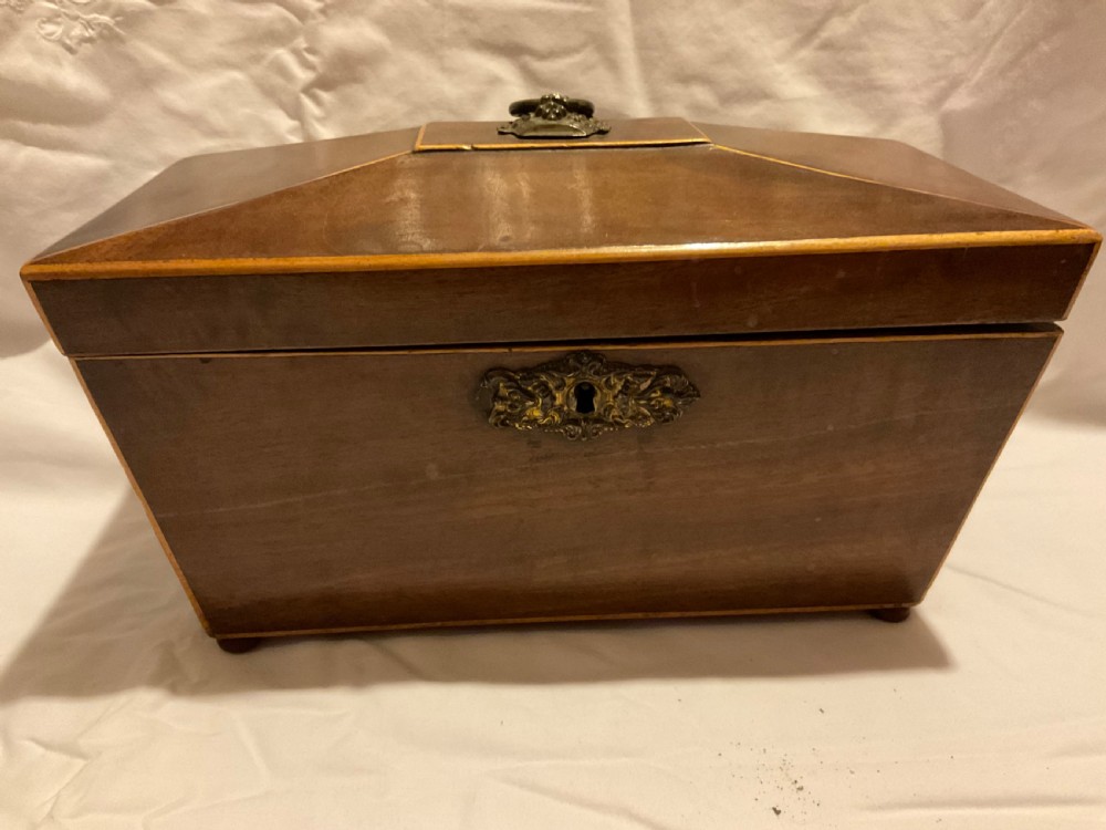 A tapered Georgian mahogany tea caddy with boxwood stringing, top brass handle, and decorative brass keyhole escutcheon.