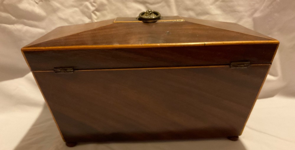 A tapered Georgian mahogany tea caddy with boxwood stringing, top brass handle, and decorative brass keyhole escutcheon. View V
