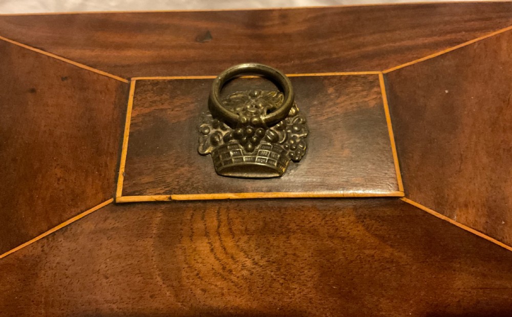 A tapered Georgian mahogany tea caddy with boxwood stringing, top brass handle, and decorative brass keyhole escutcheon. View VII