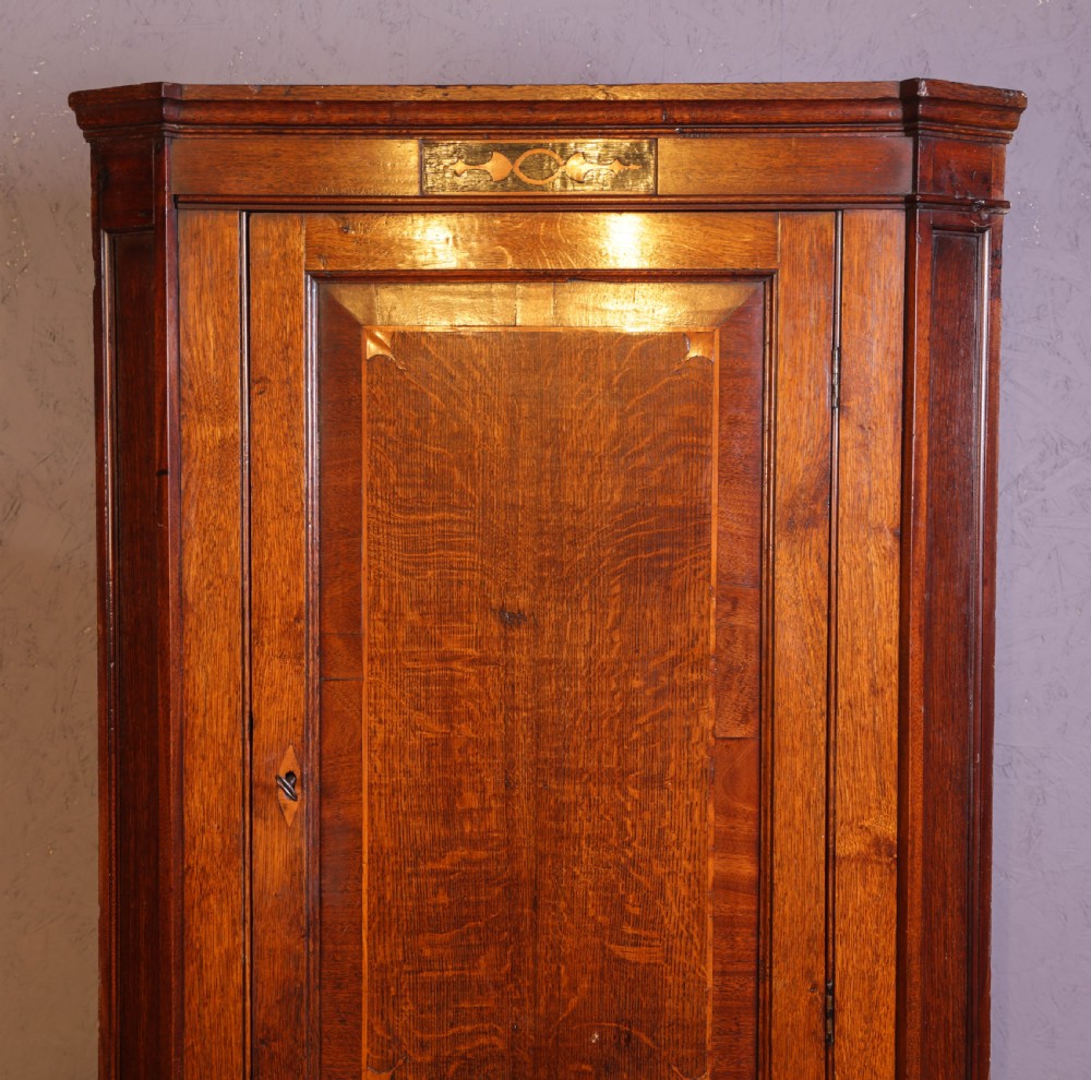 An eighteenth-century oak corner cupboard featuring a single panelled door with crossbanded inlay, a top marquetry motif, and a diamond keyhole. View V