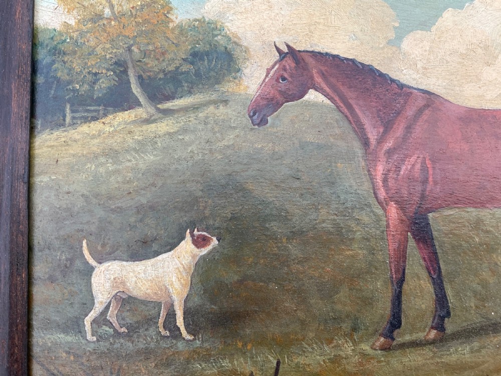 An antique oil painting depicting a chestnut horse standing alongside a small white terrier in a grassy landscape within a dark wooden frame. View IV