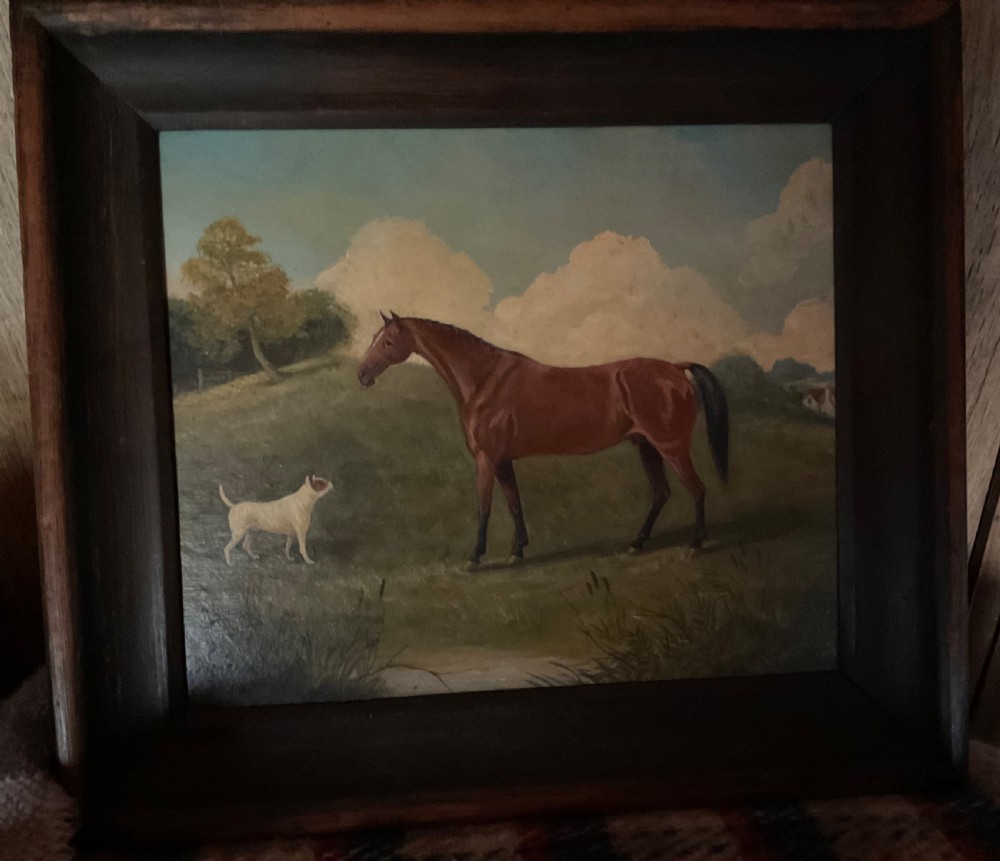 An antique oil painting depicting a chestnut horse standing alongside a small white terrier in a grassy landscape within a dark wooden frame. View VII