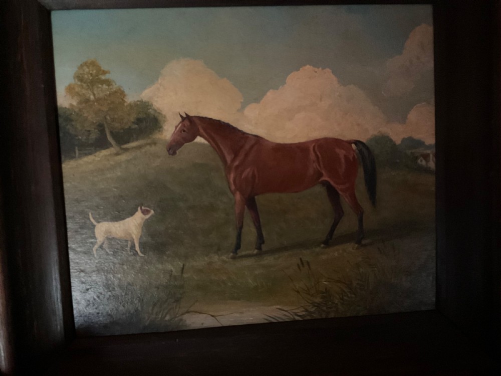 An antique oil painting depicting a chestnut horse standing alongside a small white terrier in a grassy landscape within a dark wooden frame. View VIII