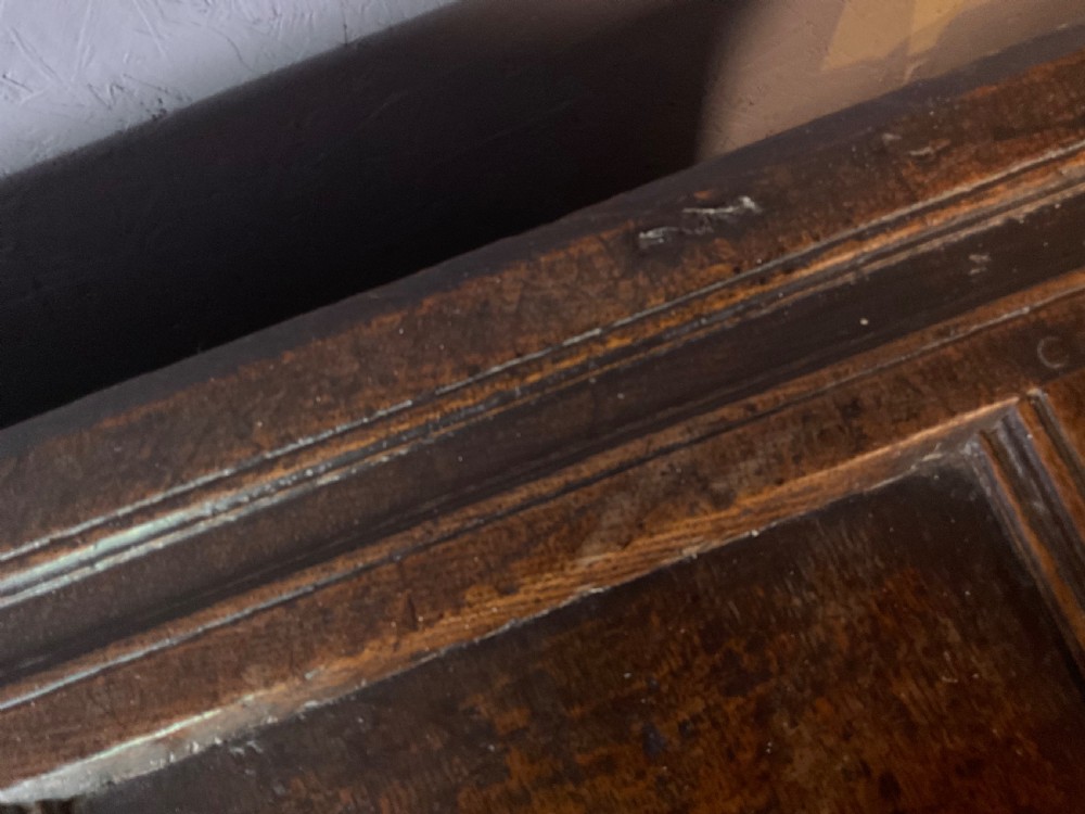A seventeenth-century dark oak coffer featuring a framed panel lid and three front panels carved with geometric lozenge patterns. View VI