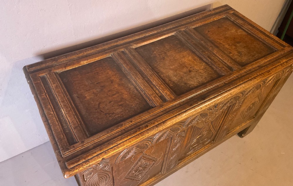 A seventeenth-century dark oak coffer featuring a framed panel lid and three front panels carved with geometric lozenge patterns. View VIII