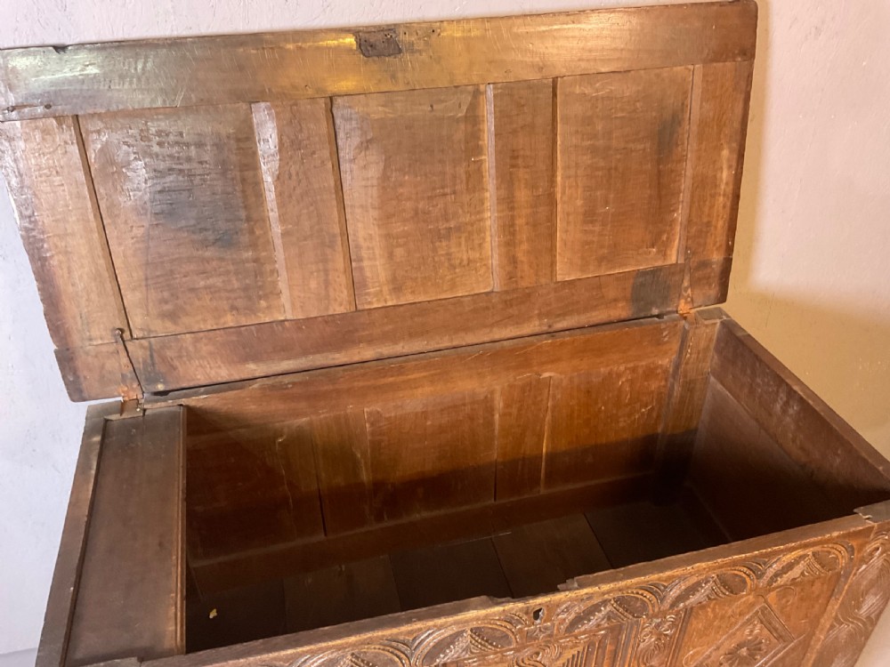 A seventeenth-century dark oak coffer featuring a framed panel lid and three front panels carved with geometric lozenge patterns. View XV