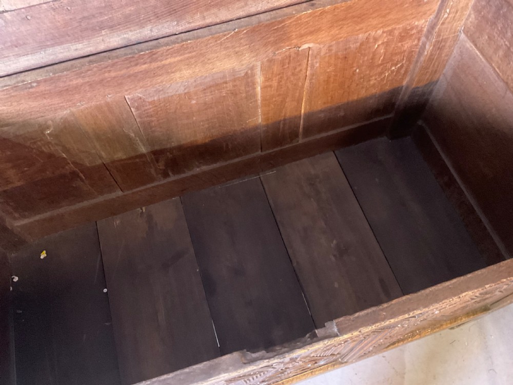 A seventeenth-century dark oak coffer featuring a framed panel lid and three front panels carved with geometric lozenge patterns. View XVI