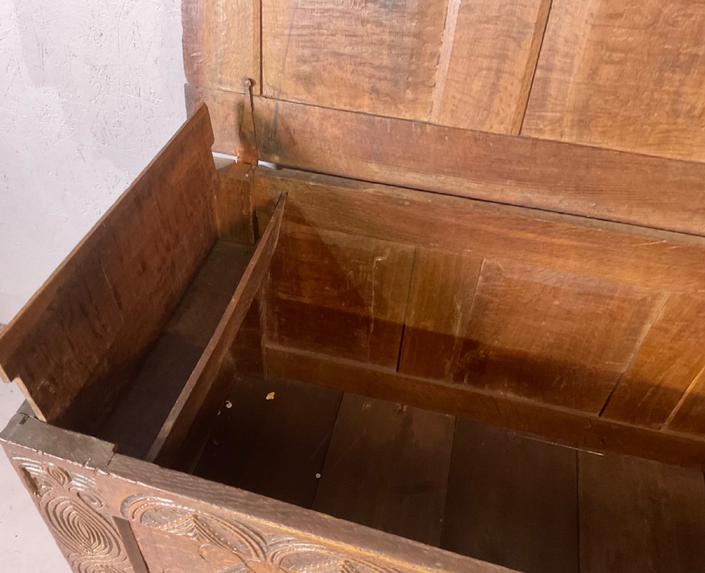 A seventeenth-century dark oak coffer featuring a framed panel lid and three front panels carved with geometric lozenge patterns. View XVII