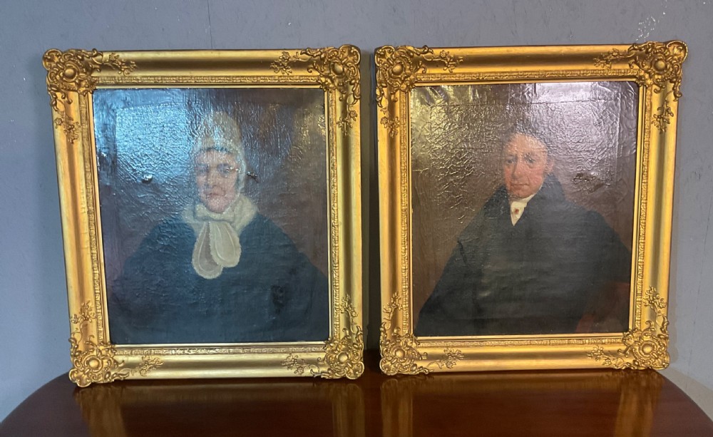 A pair of Regency period oil paintings on canvas depicting a gentleman and a lady in matching ornate gold gilt frames.