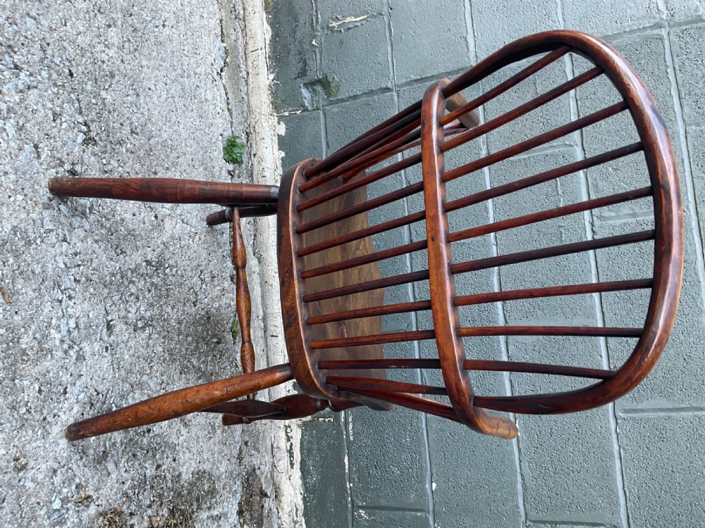 An antique yew wood Windsor armchair featuring a hoop back with vertical spindles, shaped arms, and turned wooden legs. View V