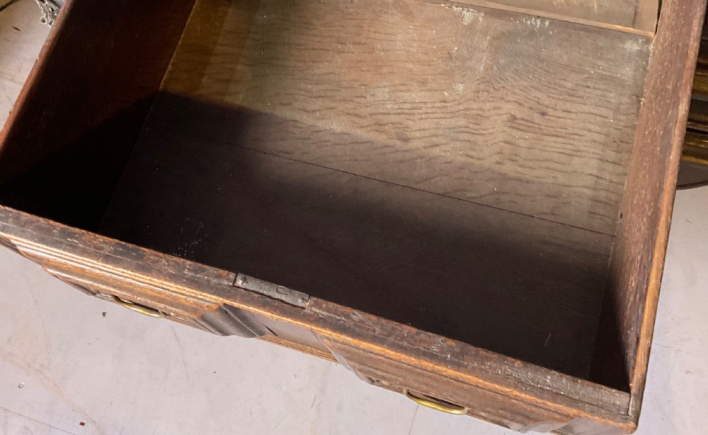 A late seventeenth-century dark oak serving dresser featuring three geometric moulded drawers with brass handles and a scalloped lower apron set on turned legs. View XII
